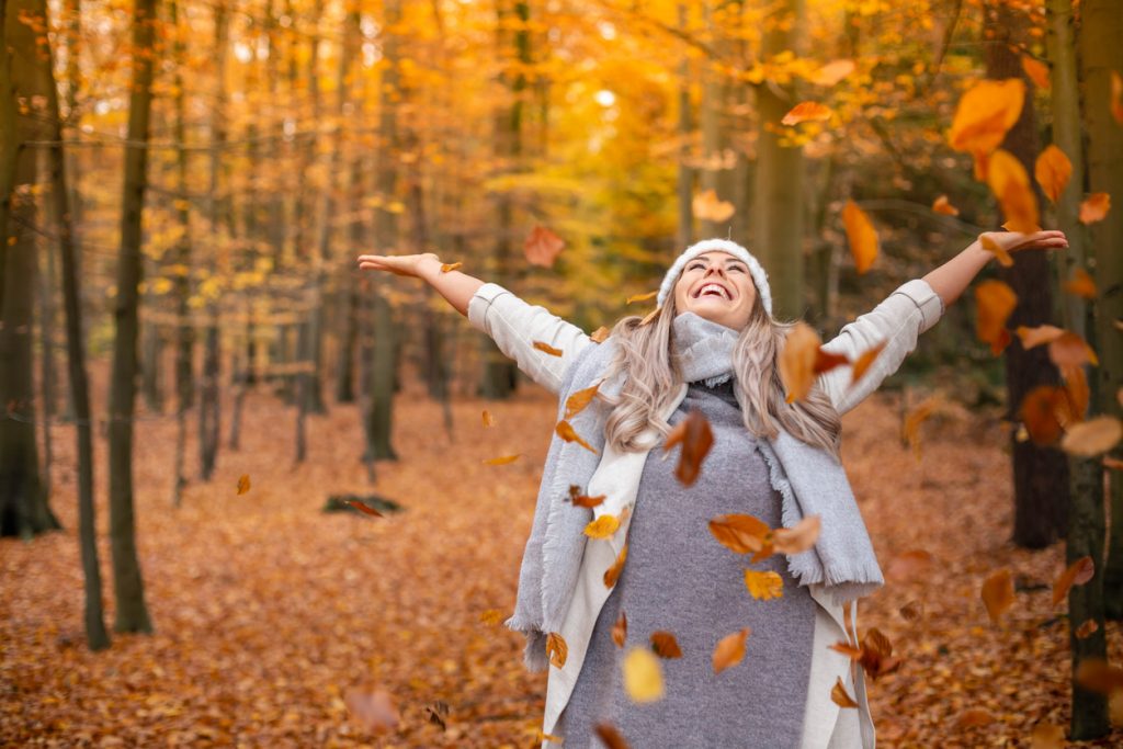 Happy image of a smiling woman throwing autumn leaves into the air ELEMENTAL SOLES