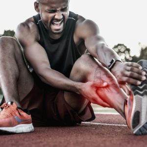 Black male athlete crouching in pain clutching lower leg ELEMENTAL SOLES